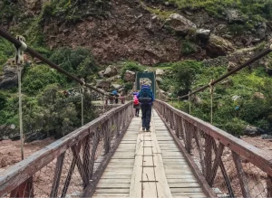 Caminantes cruzando el puente sobre el río Urubamba al inicio del Camino Inca