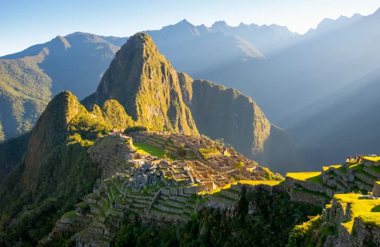 Cusco Histórico - Vista panorámica de Machu Picchu con montañas verdes y nubes alrededor.