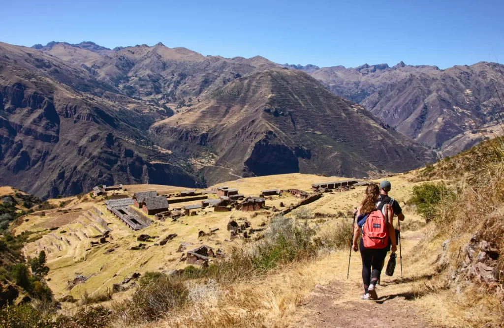 Vista panorámica de las ruinas de Huchuy Qosqo con el Valle Sagrado de fondo, rodeado de montañas.