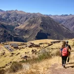 Vista panorámica de las ruinas de Huchuy Qosqo con el Valle Sagrado de fondo, rodeado de montañas.
