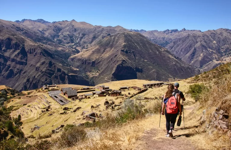 Vista panorámica de las ruinas de Huchuy Qosqo con el Valle Sagrado de fondo, rodeado de montañas.
