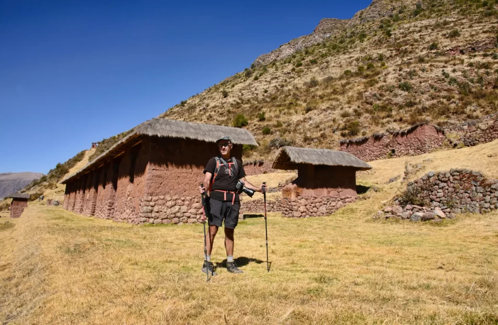 Exploradores disfrutando de la vista de las ruinas de Huchuy Qosqo con el paisaje del Valle Sagrado de fondo.