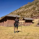 Exploradores disfrutando de la vista de las ruinas de Huchuy Qosqo con el paisaje del Valle Sagrado de fondo.