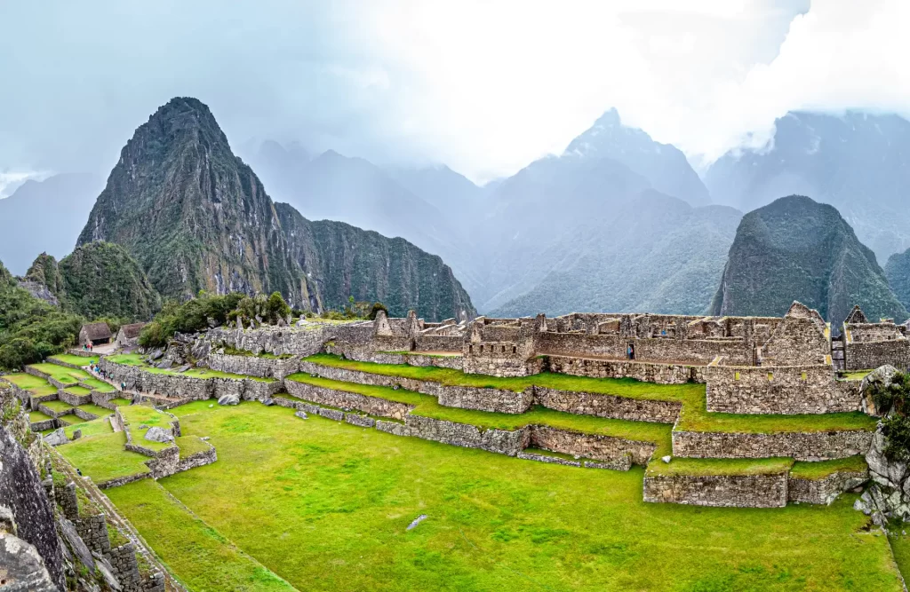 Descubriendo Cusco en 7 días - Un primer plano de una llama pastando en las ruinas de Machu Picchu, con las montañas Huayna Picchu y Machu Picchu en el fondo.