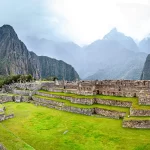 Descubriendo Cusco en 7 días - Un primer plano de una llama pastando en las ruinas de Machu Picchu, con las montañas Huayna Picchu y Machu Picchu en el fondo.