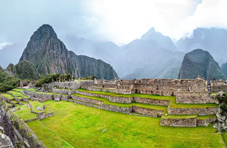 Descubriendo Cusco en 7 días - Un primer plano de una llama pastando en las ruinas de Machu Picchu, con las montañas Huayna Picchu y Machu Picchu en el fondo.