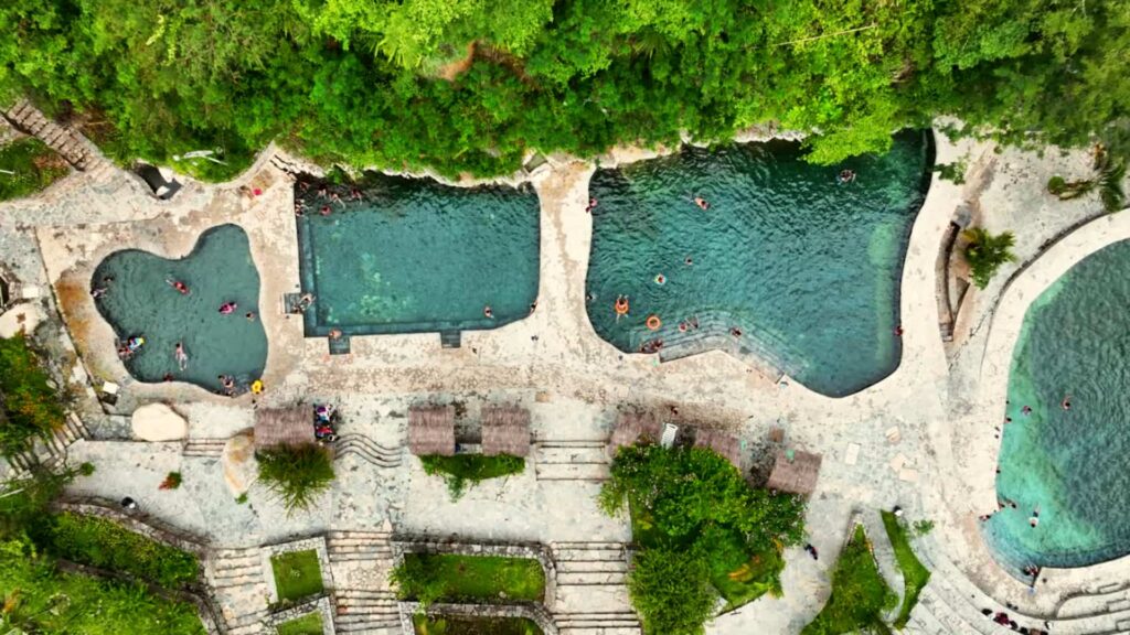 Vista aérea de las piscinas termales de Cocalmayo en Santa Teresa, rodeadas de selva y con bañistas