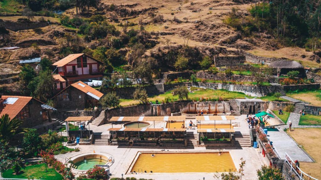 Complejo de aguas termales de Lares con piscinas de agua amarillenta entre terrazas y cerros andinos