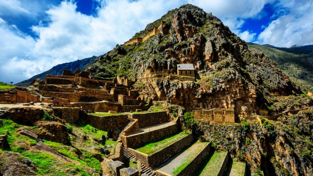 Ruinas incas de Ollantaytambo con sus terrazas y los antiguos depósitos en el cerro, bajo un cielo con nubes