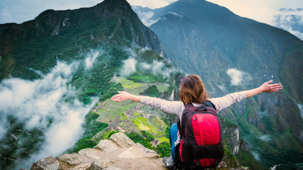 Viajera con mochila contemplando Machu Picchu desde lo alto al final del Camino Inca