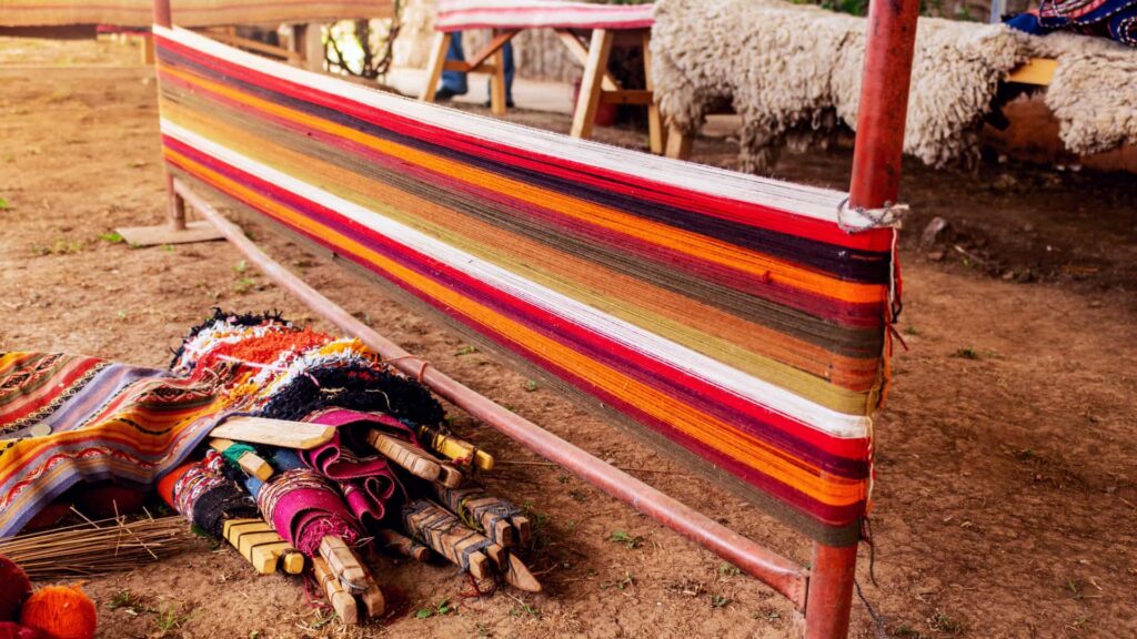 Telar andino tradicional con urdimbre de colores e instrumentos de tejido en una comunidad de Cusco