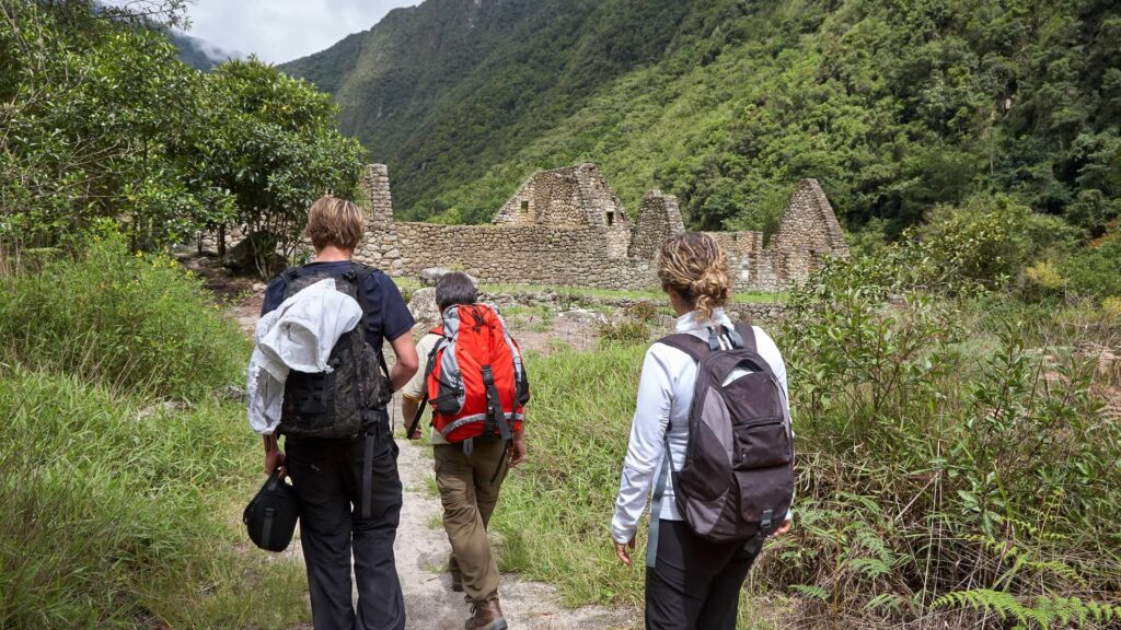 Grupo de caminantes llegando a un sitio arqueológico inca rodeado de vegetación en el Camino Inca