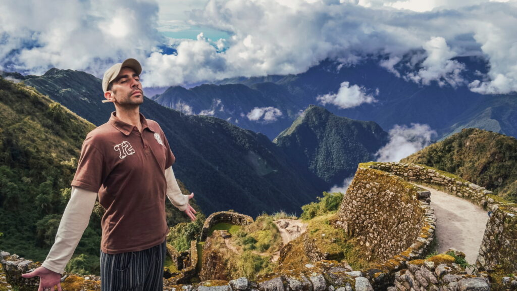 Caminante contemplando las montañas desde un antiguo recinto inca durante el Camino Inca