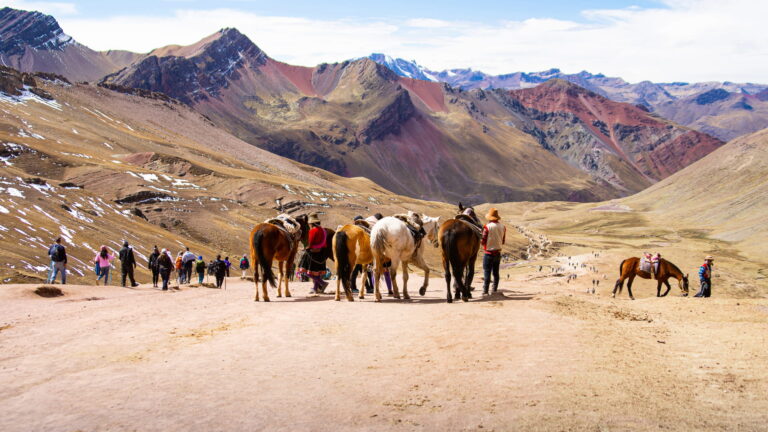 Viajeros y pobladores locales con caballos en la ruta a Vinicunca, promoviendo el Turismo Responsable en Cusco - Cusco tu Destino Travel