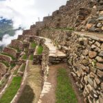 Caminando por los estrechos pasillos de las terrazas agrícolas de Choquequirao, con una vista vertiginosa del cañón cubierto de nubes.