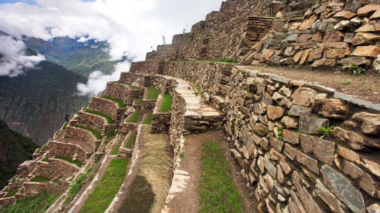 Caminando por los estrechos pasillos de las terrazas agrícolas de Choquequirao, con una vista vertiginosa del cañón cubierto de nubes.