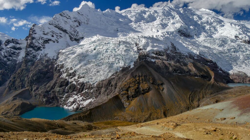 Impresionante vista del Nevado Ausangate con su glaciar descendiendo hacia una laguna de intensas aguas turquesas.