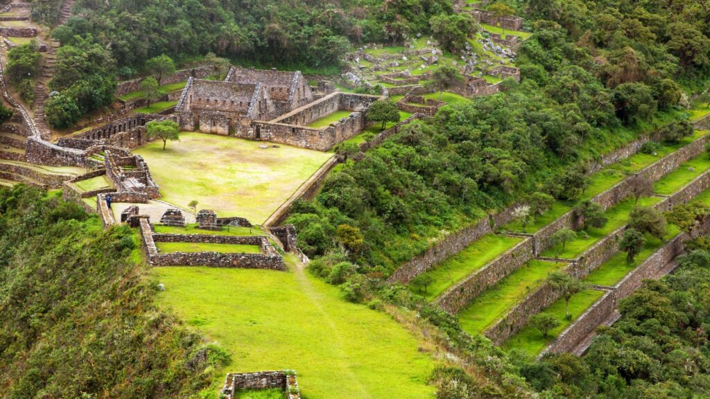 Vista panorámica de la plaza principal y las terrazas agrícolas incas del sitio arqueológico de Choquequirao, rodeado de vegetación andina.
