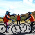 Un grupo de viajeros con cascos y equipo de protección se prepara para un tour de ciclismo inka Jungle guiado en una carretera de alta montaña.