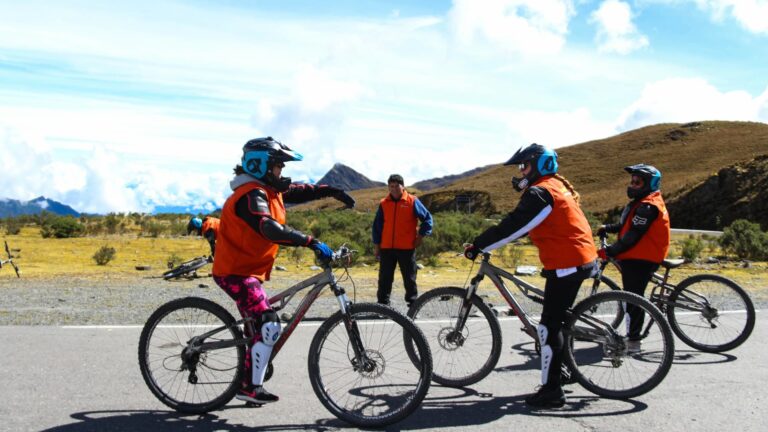 Un grupo de viajeros con cascos y equipo de protección se prepara para un tour de ciclismo inka Jungle guiado en una carretera de alta montaña.