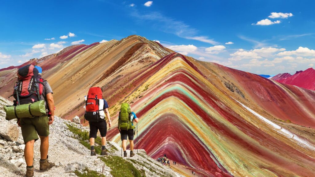Excursionistas con mochilas caminando por el sendero que lleva a la cumbre de la Montaña de 7 Colores, Vinicunca.