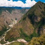 Vista panorámica desde lo alto del Camino Inca - Inka Jungle, mostrando el profundo cañón del río Urubamba serpenteando entre majestuosas montañas verdes.