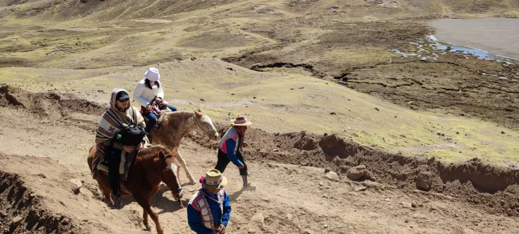 Viajeras a caballo guiadas por arrieros de la comunidad en la subida a Vinicunca