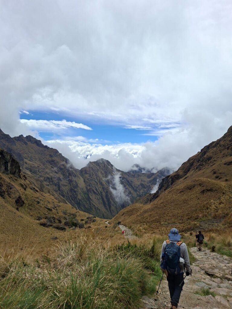 Caminante en el sendero del Camino Inca entre montañas y nubes