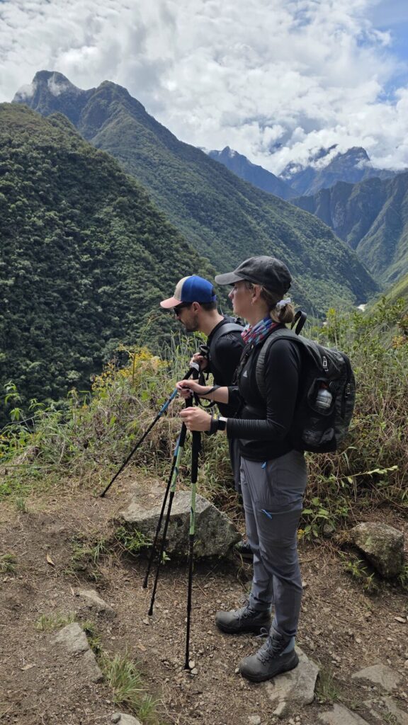 Caminantes con bastones en el sendero del Camino Inca con vista al valle