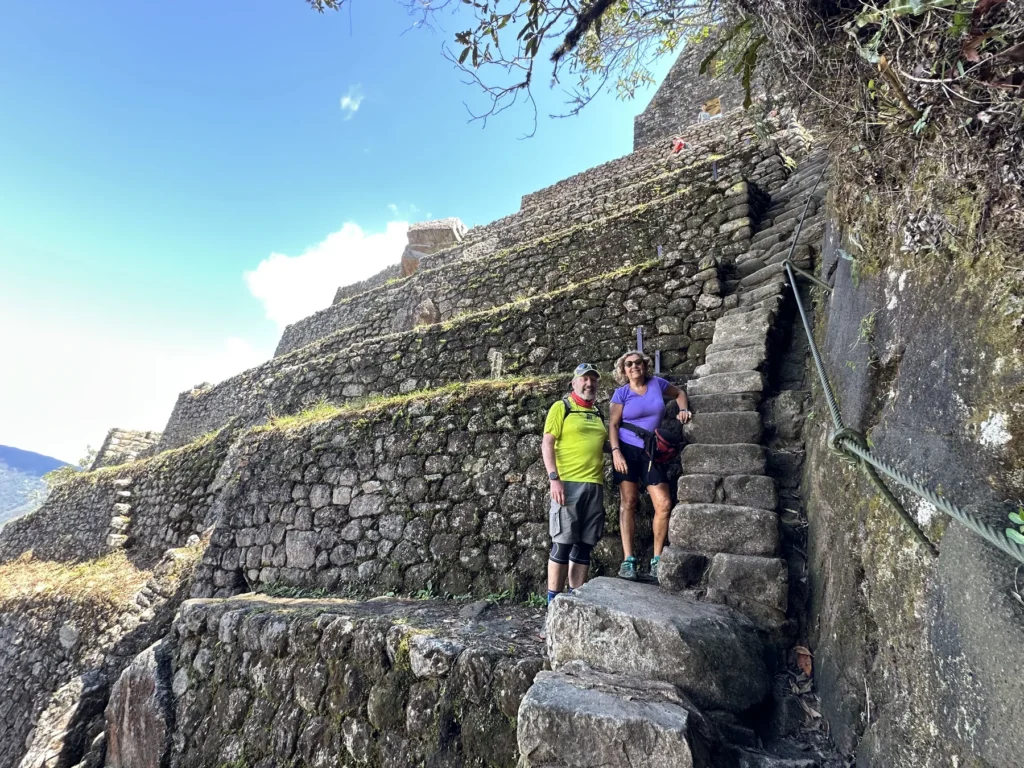 Viajeros en la escalinata de piedra junto a los andenes de la cumbre de Huayna Picchu