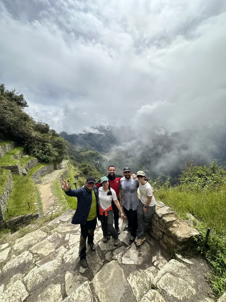 Grupo de viajeros en una escalinata inca del Camino Inca con montañas cubiertas de nubes