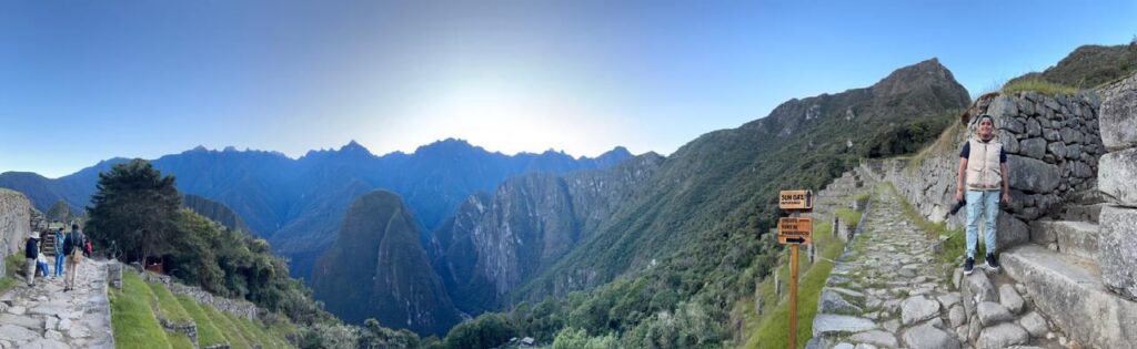 Vista panorámica del sendero inca junto a un muro de piedra y el valle de Machu Picchu