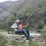 Viajera cruzando el río en oroya (canastilla colgada de un cable) durante el Inka Jungle