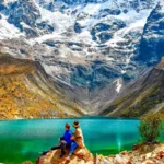 Pareja sentada sobre una roca frente a la Laguna Humantay