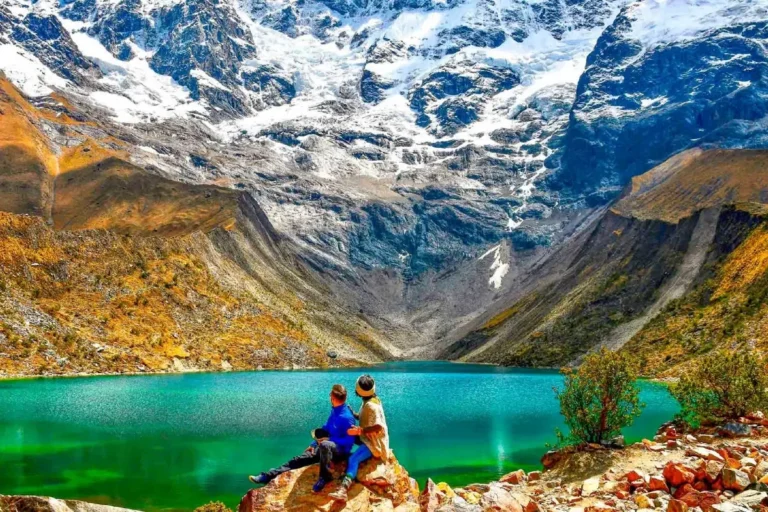 Pareja sentada sobre una roca frente a la Laguna Humantay