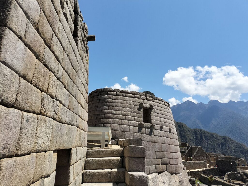 Muro curvo del Templo del Sol de Machu Picchu con las montañas al fondo