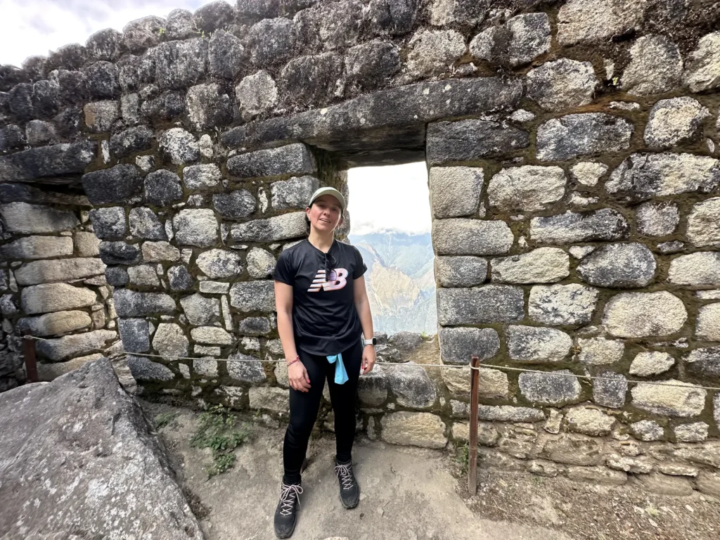 Viajera junto a una ventana de muro inca en los recintos de la cima de Huayna Picchu