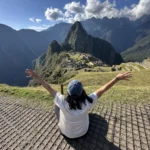 Viajera con los brazos abiertos frente a la vista clásica de Machu Picchu y Huayna Picchu