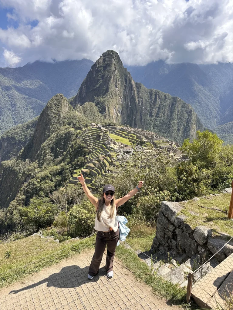 Viajera saludando en Machu Picchu con el Huayna Picchu y los andenes al fondo