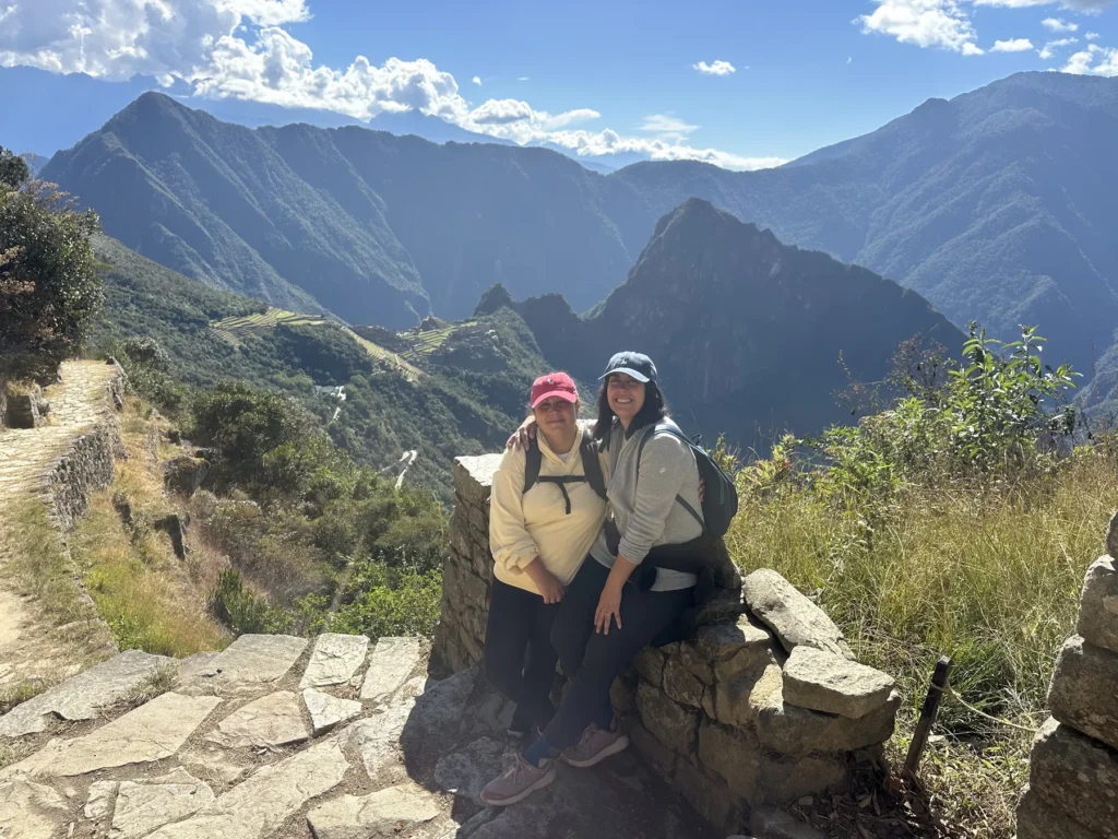 Viajeras descansando sobre un muro inca con vista a las montañas que rodean Machu Picchu