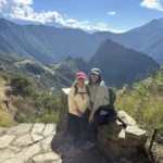 Viajeras descansando sobre un muro inca con vista a las montañas que rodean Machu Picchu