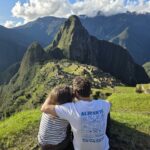 Viajeros abrazados contemplando Machu Picchu desde las terrazas altas