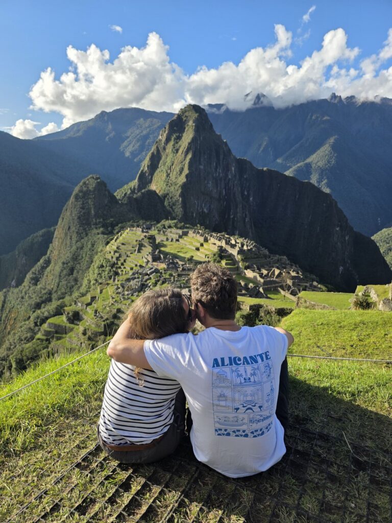 Viajeros abrazados contemplando Machu Picchu desde las terrazas altas
