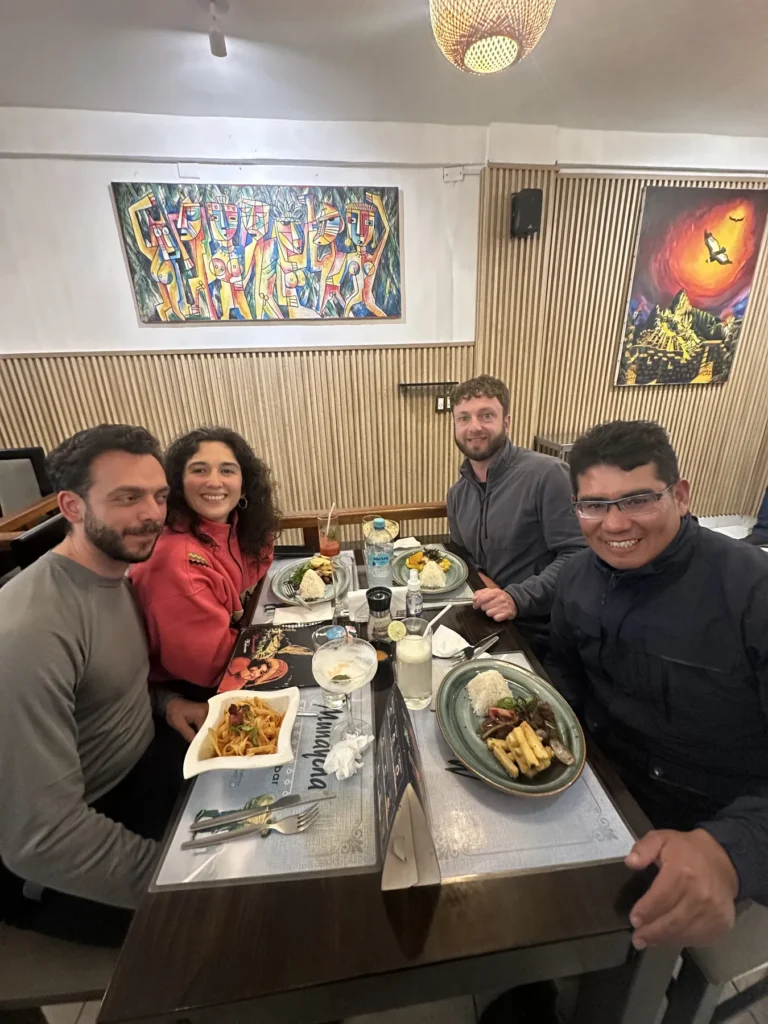 Viajeros compartiendo una cena de comida cusqueña con su guía en un restaurante de Cusco