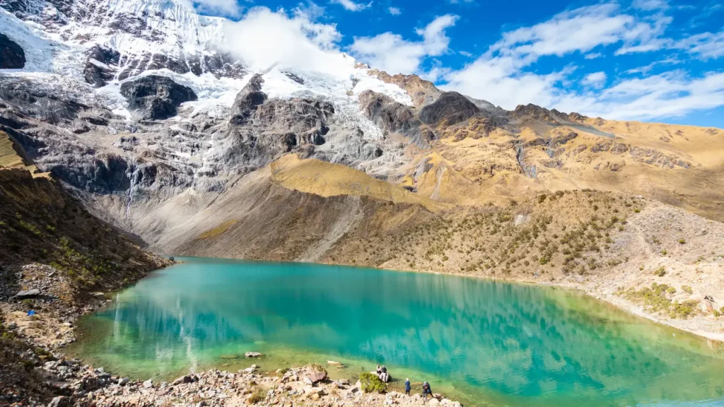 Viajeros en la orilla de la Laguna Humantay en un día despejado