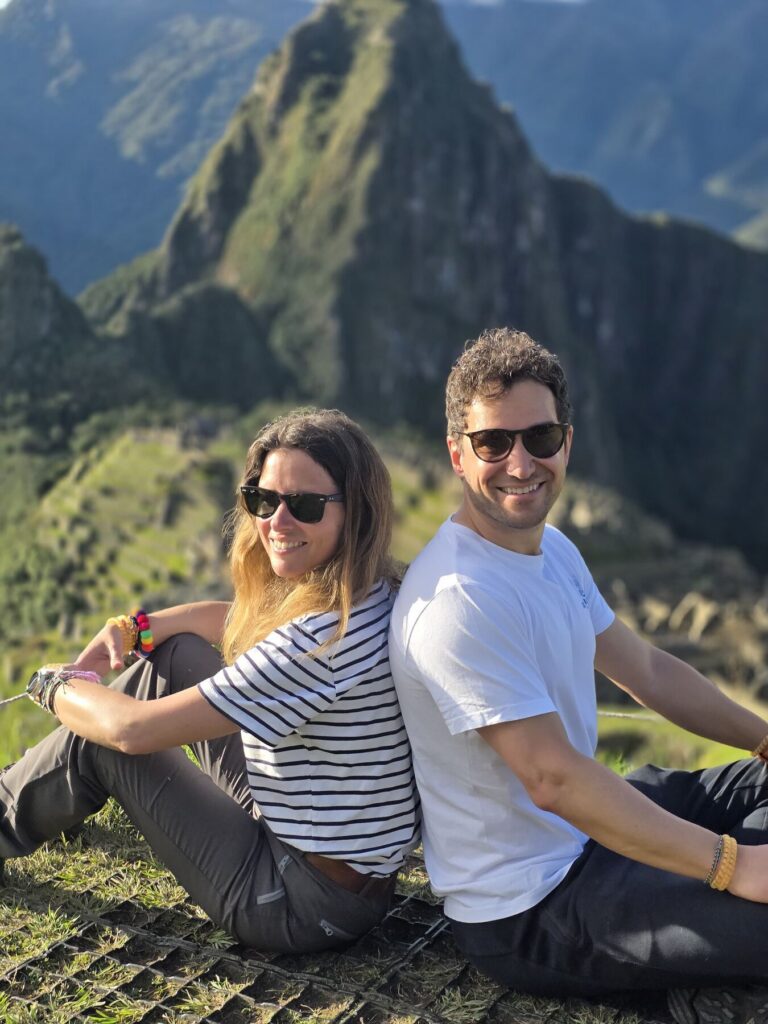 Pareja de viajeros sentados frente a Machu Picchu y el Huayna Picchu