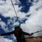 Turista con casco grabándose con una cámara en la tirolesa (zip line) de Cusco